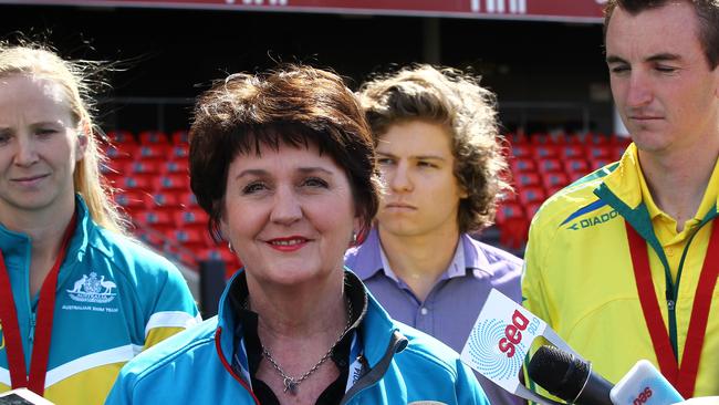 Jann Stuckey flanked by Gold Coast Commonwealth Games medallists Melanie Wright (left) and Michael Shelly (right) at the unveiling of the games flag at Metricon Stadium.