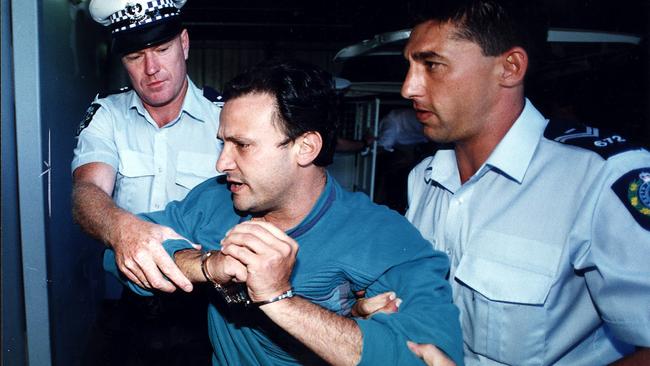 Dominic Perre in handcuffs after being arrested for bombing NCA building in Adelaide.