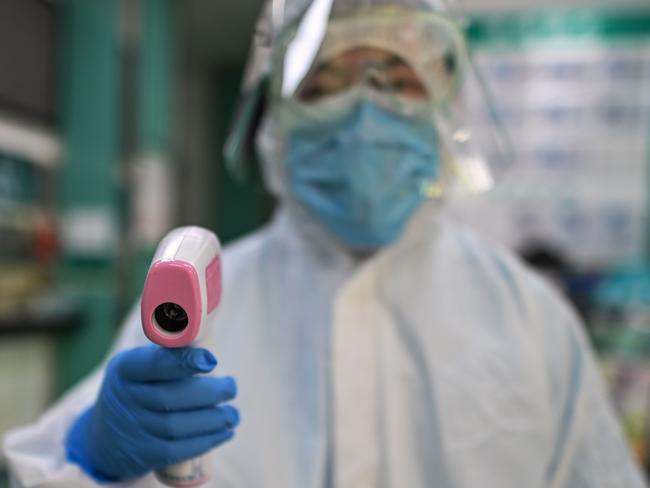 TOPSHOT - A medical worker prepares to check the temperature of an AFP photojournalist before a COVID-19 coronavirus test in Wuhan in China's central Hubei province on April 16, 2020. - China has largely brought the coronavirus under control within its borders since the outbreak first emerged in the city of Wuhan late last year. (Photo by Hector RETAMAL / AFP)