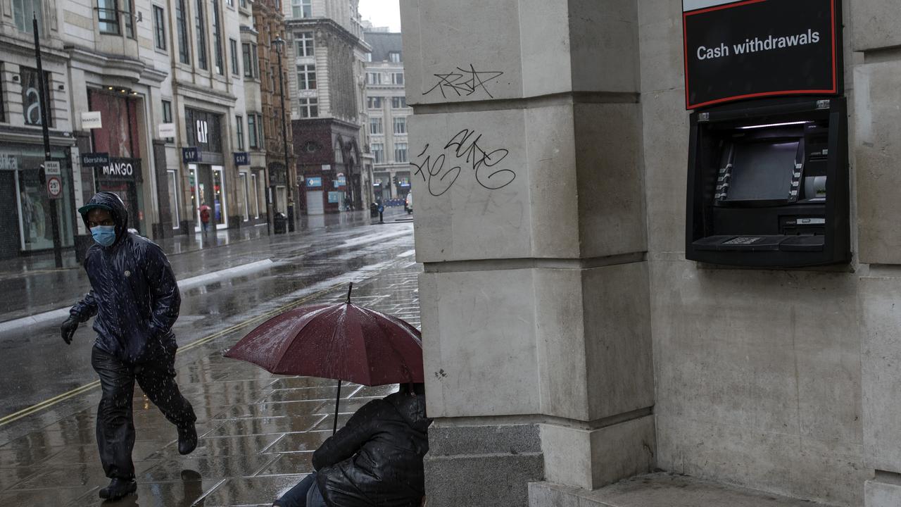 A man wearing a face mask runs through the rain past a homeless man on Oxford Street on May 1, 2020 in London, England. Picture: Dan Kitwood/Getty Images