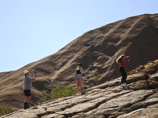 Tourists are seen taking pictures as they start climbing Uluru, also known as Ayers Rock at Uluru-Kata Tjuta National Park in the Northern Territory, Friday. Picture: AAP