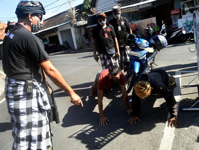 Bali traditional security Pecalang punish riders not wearing face masks with 20 push-ups in Sanur, Bali. Picture. Yuda