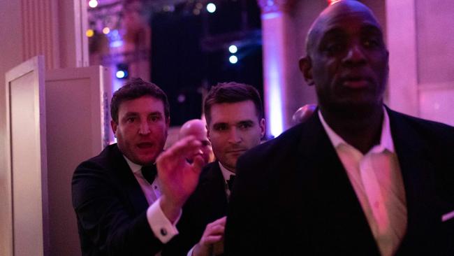 US political strategist Alex Bruesewitz (centre) is escorted backstage after collapsing on stage. Picture: AFP.