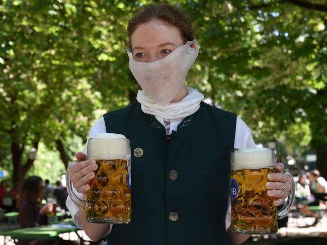 A waitress wears a protective mask and serves beer mugs in a beer garden in Munich. Picture: AFP