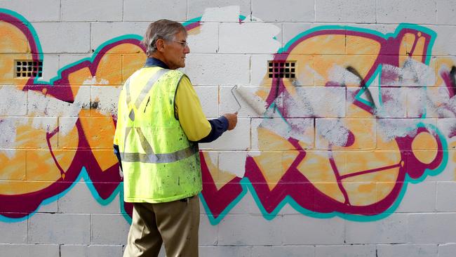 John Oakey in action painting over the graffiti.