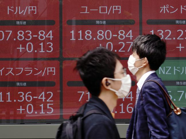 Men wearing masks walk past an electronic stock board showing foreign currency exchange rates at a securities firm in Tokyo Thursday, May 28, 2020. Asian stocks are mixed after an upbeat open, as hopes for an economic rebound from the coronavirus crisis were dimmed by tensions between the U.S. and China over Hong Kong and other issues. (AP Photo/Eugene Hoshiko)