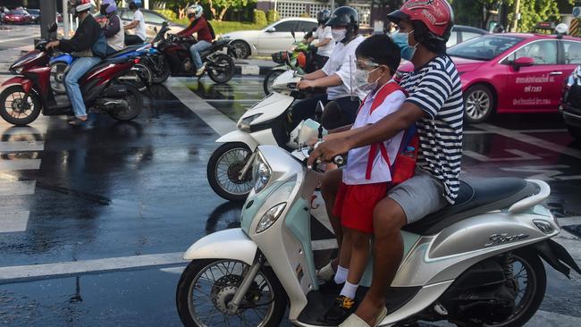 A school child is given a lift in Bangkok, Thailand. Picture: AFP