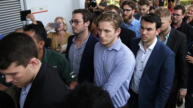 Handcuffed and wearing another sort of uniform, the Budgie Nine file into court before their acquittal. Picture: Jack Tran