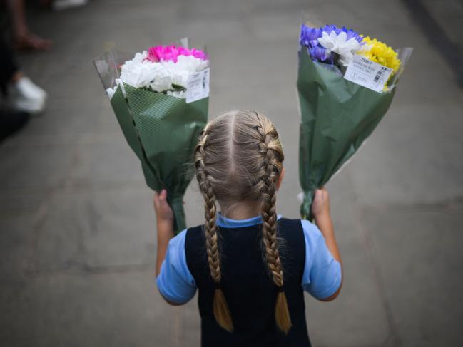 A child carries two bouquets of flowers to be placed at the floral tribute outside of Windsor Castle, west of London. Picture: AFP