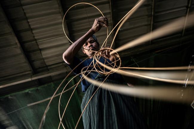 A man weaves cane into a traditional Myanmar chinlone ball at a workshop in Hinthada township in the Irrawaddy delta