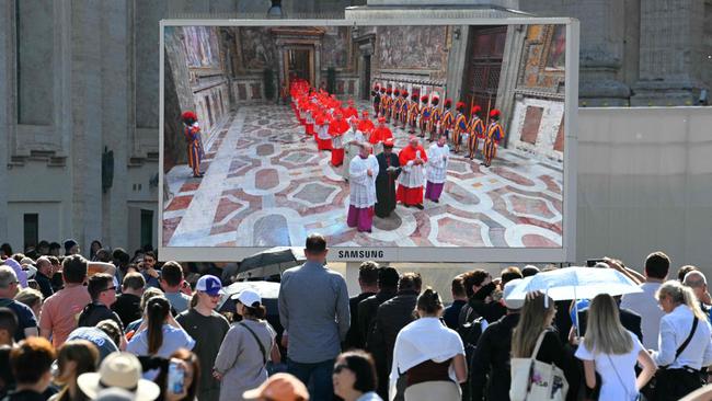 Faithful watch giant screen displaying images of the procession of cardinals to the Sistine Chapel. Picture: AFP