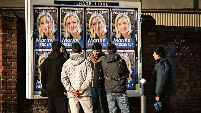 Migrants beside Le Pen’s election posters.