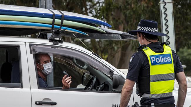 A police officer checks for entry permits to Victoria at a border checkpoint in Mallacoota. Picture: Diego Fedele/Getty Images