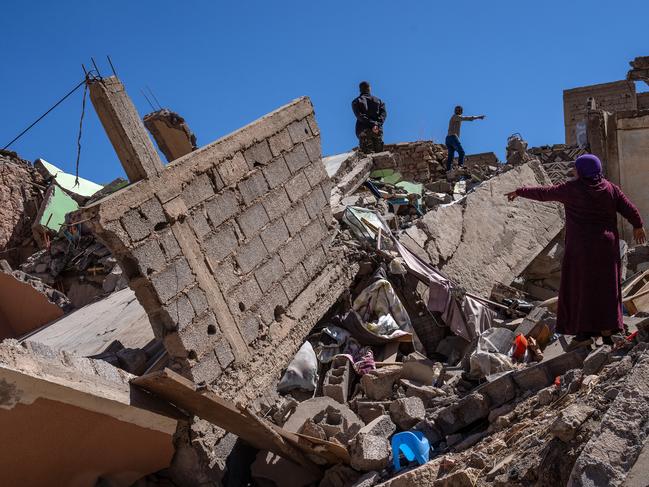 A brother and sister gesture to each other as they search the remains of the sister's home following the earthquake. Picture: Getty Images