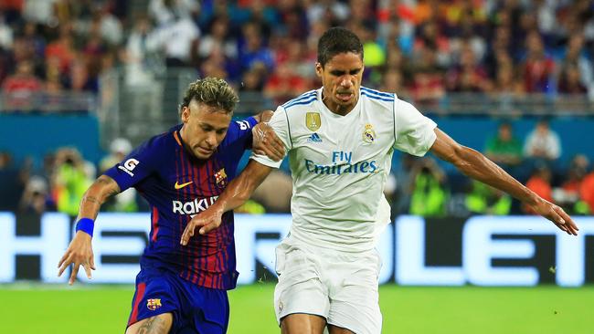 Neymar of Barcelona vies for the ball with Raphael Varane of Real Madrid
