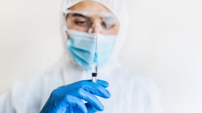 Doctor / medical worker holding a syringe with vaccine in his hand. Coronavirus vaccination concept. istock image