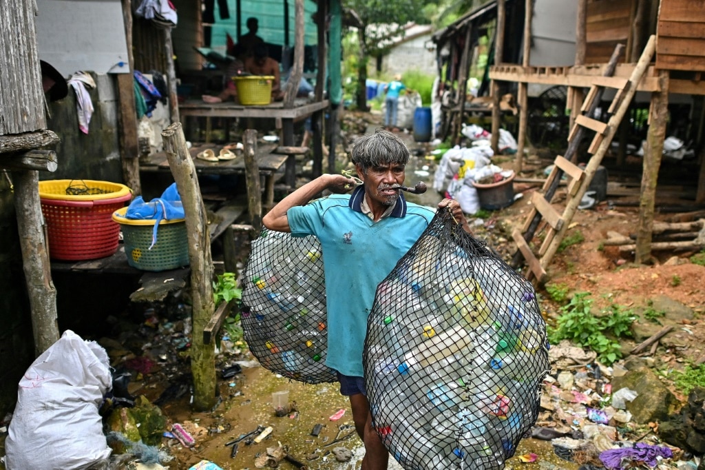 A Moken fisherman carries bags of plastic waste to sell to Tide staff members at his fishing village on Thailand's southern island of Koh Chang