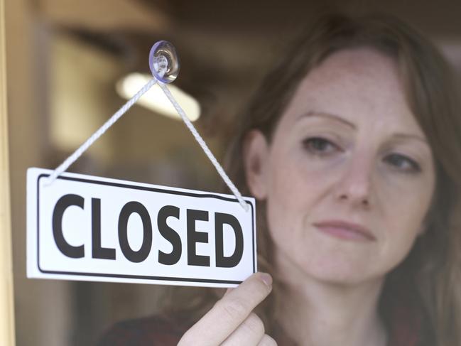 Store Owner Turning Closed Sign In Shop Doorway