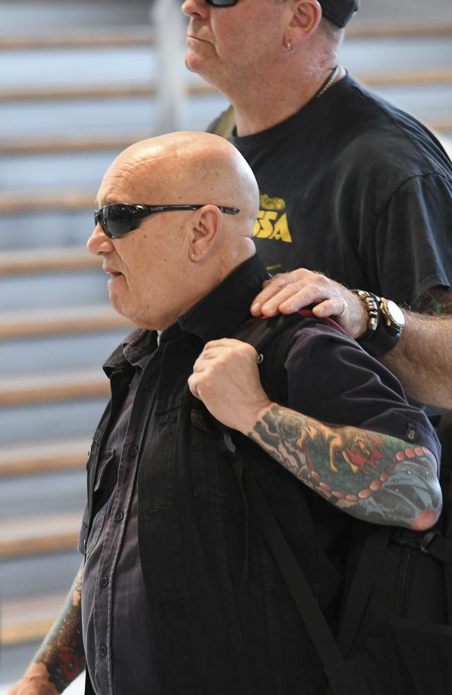 Angry Anderson is supported by a friend as he arrives at Sydney Airport under heavy security on Sunday.