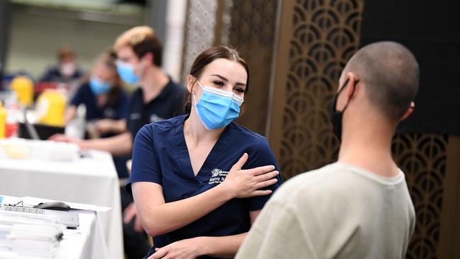 Health worker Jamie Butler talks to a man before he is vaccinated. Picture: NCA NewsWire / Dan Peled