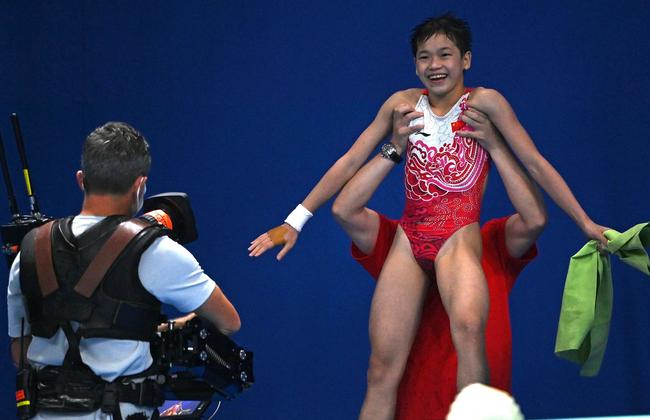 After receiving a near perfect score in the Women’s 10m platform diving event, China's Quan Hongchan is lifted up by her coach. Picture: Attila Kisbenedek / AFP