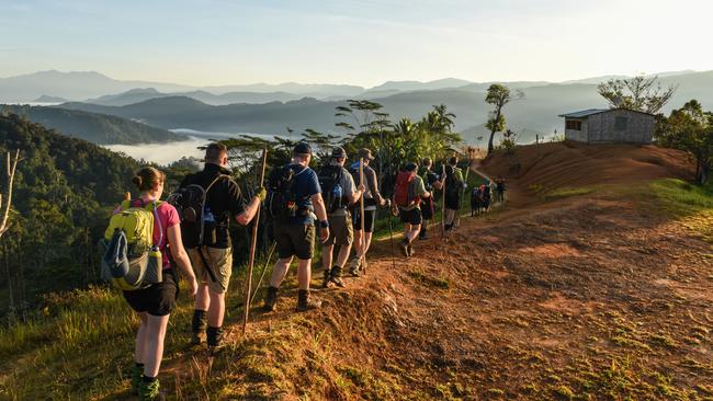 Trekkers and their porters from Buna pass the village of Nauro on the Kokoda Trek. Picture: Brad Fleet