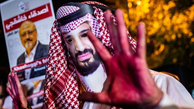 A protestor wears a mask of depicting Saudi Crown Prince Mohammad Bin Salman with red painted hands next to people holding posters of Saudi journalist Jamal Khashoggi during a demonstration outside the Saudi Arabia consulate in Istanbul. Photo: AFP