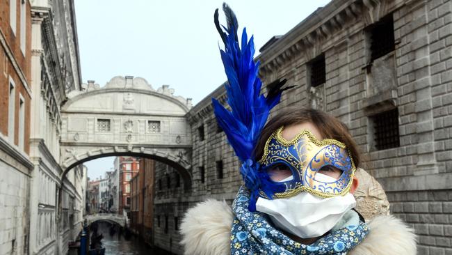 A young tourist wearing a protective facemask and a Carnival mask visits the streets of Venice last week during the usual period of the Carnival festivities Picture: AFP