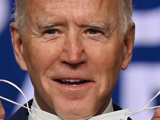 TOPSHOT - Democratic Presidential candidate Joe Biden removes his mask before speaking at the Chase Center in Wilmington, Delaware on November 4, 2020. - President Donald Trump and Democratic challenger Joe Biden are squaring off for what could be a legal battle for the White House, running neck-and-neck in the electoral vote count, and several battleground states still in play on November 4. (Photo by JIM WATSON / AFP)