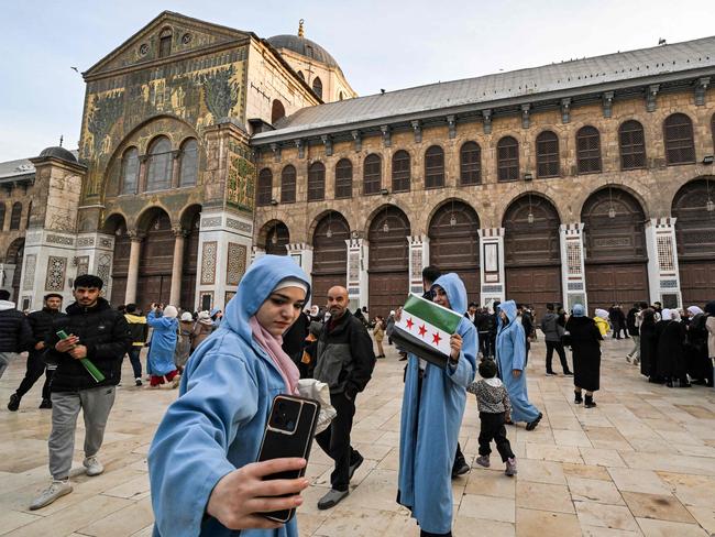 A woman films with a phone while walking in the courtyard of the 8th-century Omayyad Mosque in Damascus on Tuesday. Picture: AFP