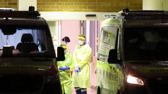 More than 1000 people are currently hospitalised in NSW with Covid. Pictured is a paramedic in full PPE next to ambulances outside Concord Hospitals emergency department on Saturday. Picture: Damian Shaw