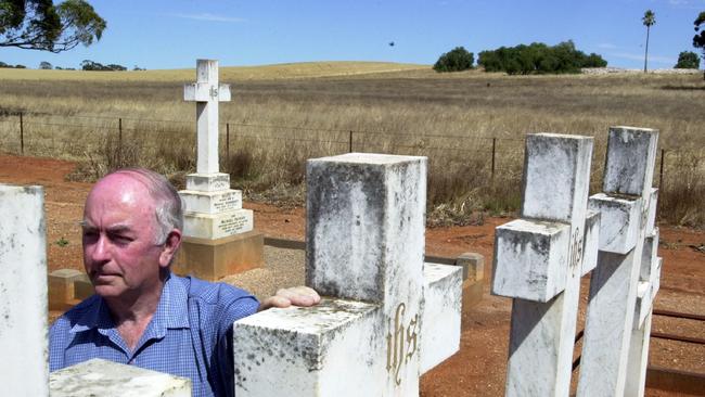 Peter Swann at St John's cemetery in Kapunda in 2002. The rubble remains of the reformatory are in background near the palm tree.