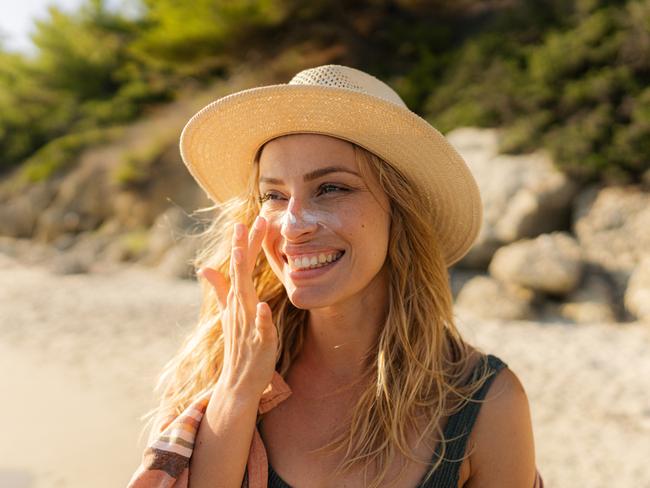 Photo of a young woman applying sunscreen on her face