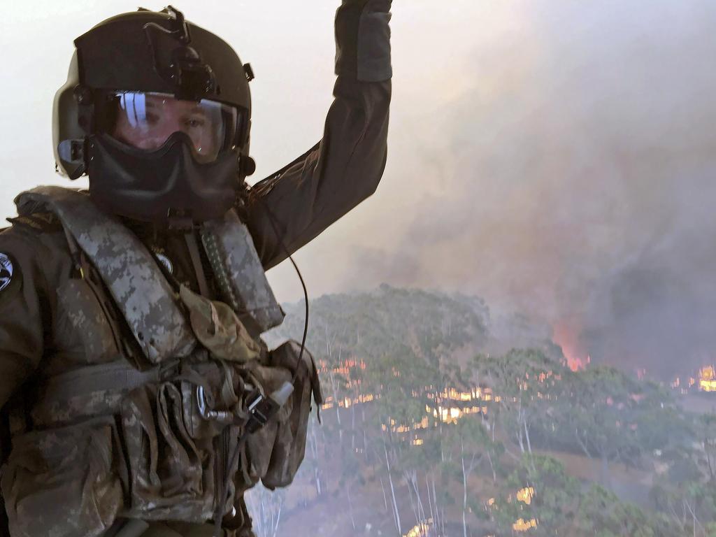 Royal Australian Navy Aircrewman, Petty Officer Jason Wickman assesses the Grose Valley bushfire in the Blue Mountains National Park during a sortie on an 808 Squadron MRH90 Taipan Military Support Helicopter. Picture: ADF