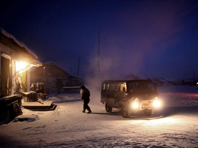 A man leaves his van and walks into Oymyakon’s only shop as paper waste is burnt in a 40 gallon drum Village of Oymyakon. Picture: Amos Chapple/REX/Shutterstock/Australscope