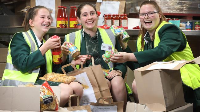 Westminster students Belle Hope, 15, Dayna Holroyd, 15, and Abigail Wicks, 15, at Foodbank where they volunteer to pack food hampers in Edwardstown, South Australia. Picture: AAP /Dean Martin