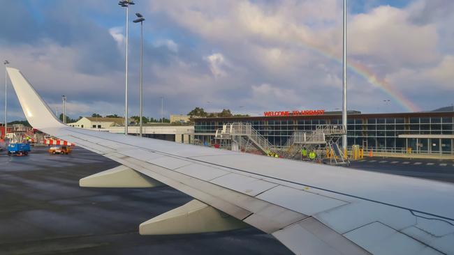 Airplane wing with rainbow. Hobart Airport building is in the background. Hobart, Tasmania, Australia. June 30, 2019.