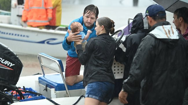 A young family are rescued by boat by David Millar as flood waters engulf Torwood and Vincent St and houses in Auchenflower, Brisbane.  Picture: The Australian / Lyndon Mechielsen