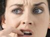 Young woman with finger in mouth, close-up, studio shot