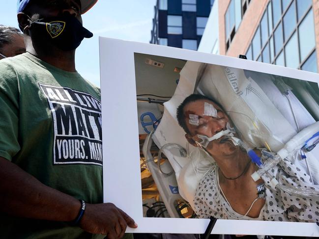 People hold a photo of  61-year old Yao Pan Ma who was was attacked from behind, pushed to the ground, and repeatedly kicked  during a press conference in Harlem April 27, 2012  at the site where the attack took place. - NYPD have taken into custody the alleged attacker 49-year-old Jarrod Powell. (Photo by TIMOTHY A. CLARY / AFP)