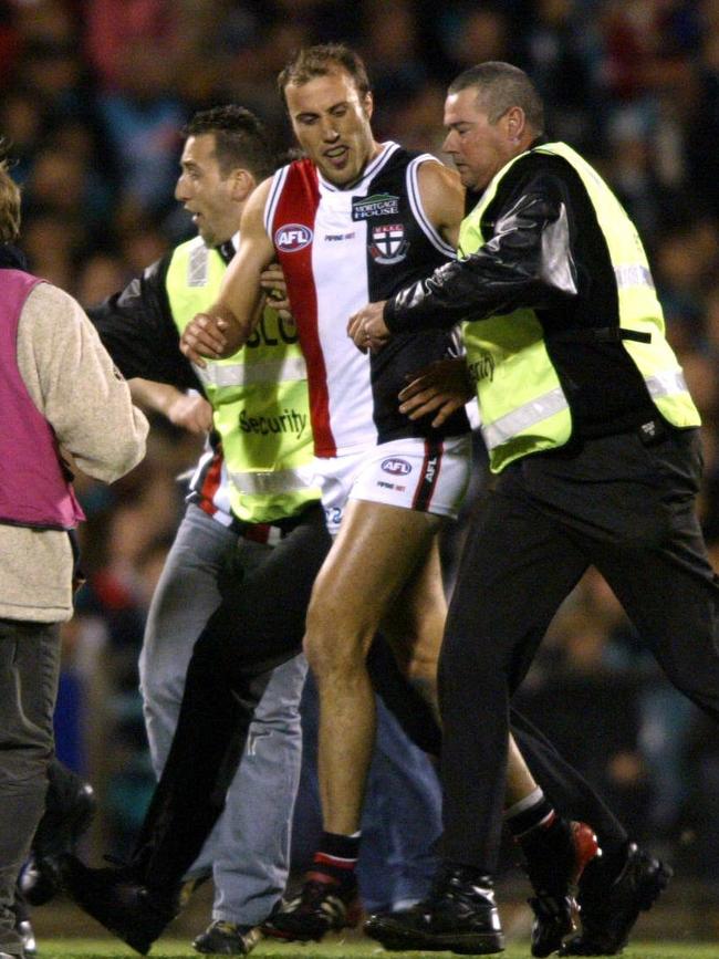 Fraser Gehrig is shepherded off the ground after kicking his 100th goal against Port at AAMI Stadium in 2004.