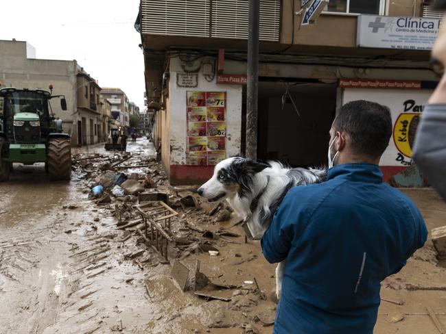 A man carries his dog on his arms as he crosses mud after heavy rain and flooding hit large parts of the country in the Massanassa municipality, in Valencia, Spain. Picture: Getty Images