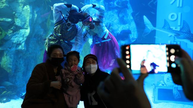 Visitors pose for photographs with divers at an event to celebrate New Year at an aquarium in Seoul, South Korea. Picture: Getty Images