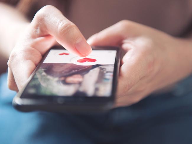 Finger of woman pushing heart icon on screen in mobile smartphone application. Online dating app, valentine's day concept.