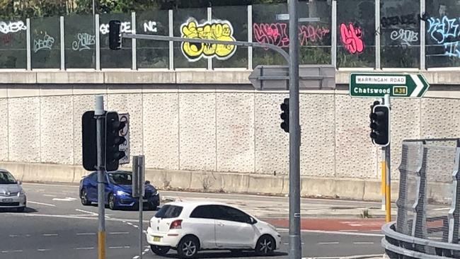 Ugly graffiti on glass panels along a pedestrian walkway above the intersection of Warringah Rd and Forest Way at Frenchs Forest. Picture: Jim O'Rourke