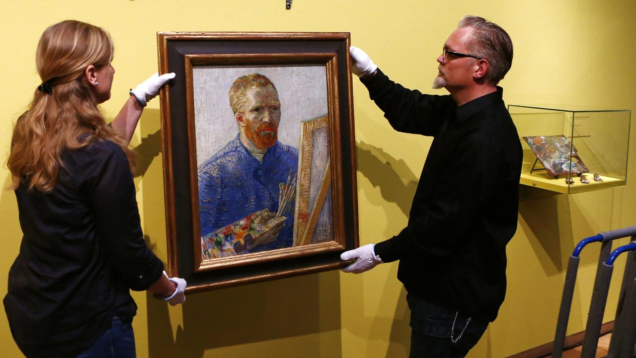 Curators hang an 1888 self-portrait of Vincent Van Gogh in which he painted himself behind a canvas, brushes and palette in hand, the final painting before the reopening after a seven-month renovation, at Van Gogh museum in Amsterdam, Netherlands, Wednesday, May 1, 2013. Displayed on the right are a wooden palette and paints that Van Gogh used in 1890. (AP Photo/Vincent Jannink) Picture: Ap
