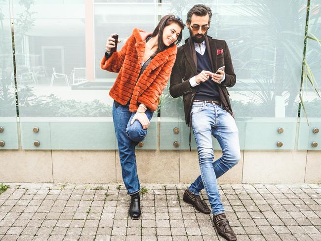 Happy hipster couple having fun with mobile smart phone at outdoors location - Friendship concept with best friends connecting and sharing content on social media - Millennial generation dating online