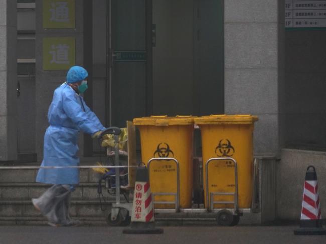 Staff move bio-waste containers past the entrance of the Wuhan Medical Treatment Center. Picture: AP