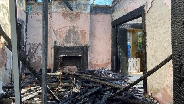 A photo of the site, including a burnt-out fireplace.