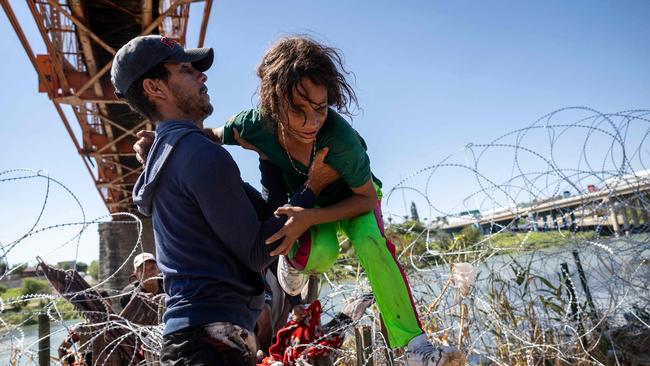 A child is helped across the wire at Eagle Pass, Texas. Picture: AFP